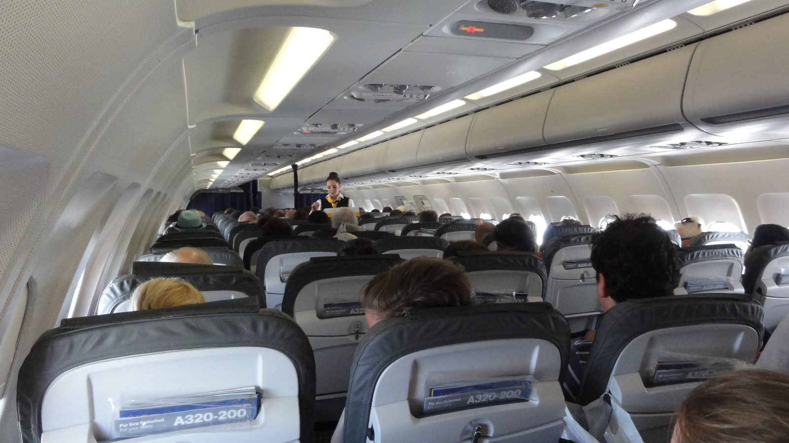 A cabin crew member serving drinks on an Airbus A320 airliner