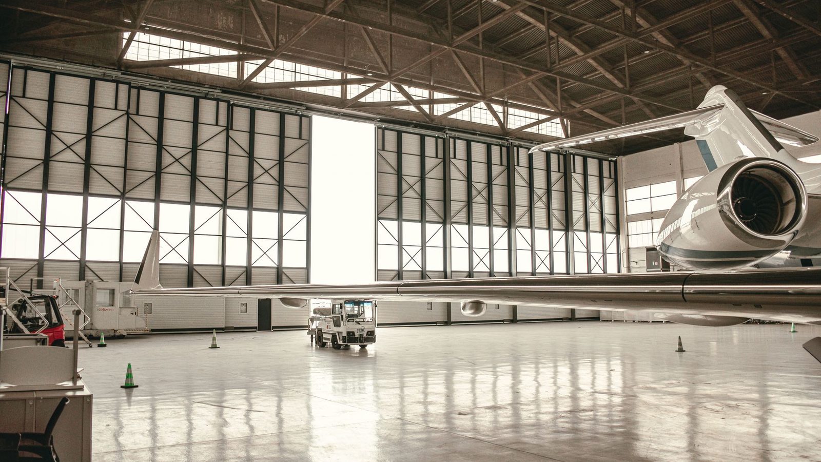 Rear fuselage and tail of a large-cabin business jet inside a hangar, doors open