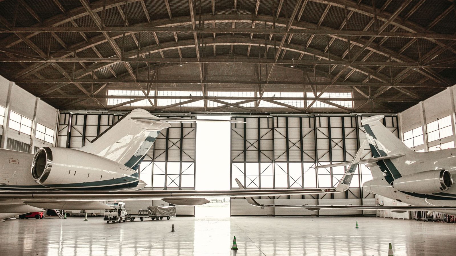 Two white business jets with rear engines parked tail-in inside a hangar